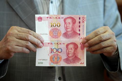 中国印钞造币总公司技术总监邵国伟在他的办公室展示新版百元钞票（上）与旧版的不同（10月30日摄）。