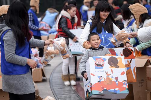 11月28日，一名小志愿者搬运装有爱心物品的“温暖包”。当日，由安徽省合肥市明光路街道、安徽民间公益组织联合举办的安徽“壹基金”温暖包分装启动仪式在合肥市和平广场举行。100余名志愿者将棉衣、帽子、手套、棉鞋、书包等物品分装到2100个“温暖包”中。这些“温暖包”将被陆续运往安徽各地的贫困儿童手中，在寒冬时节为他们带去温暖。
