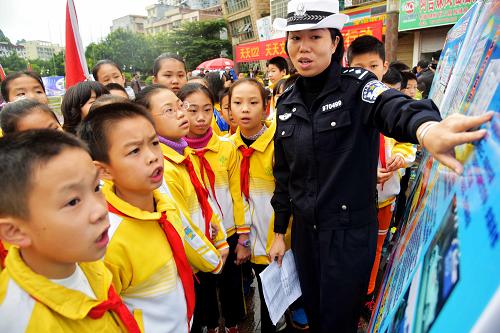 12月2日，一名广西河池交警在向学生们讲解交通安全常识。当日是“全国交通安全日”，今年安全日的主题是“拒绝危险驾驶，安全文明出行”。广西河池市交警支队组成10多个宣传组，深入到厂矿、学校、社区和街头宣传交通安全法规，倡导文明交通意识，普及交通安全知识。