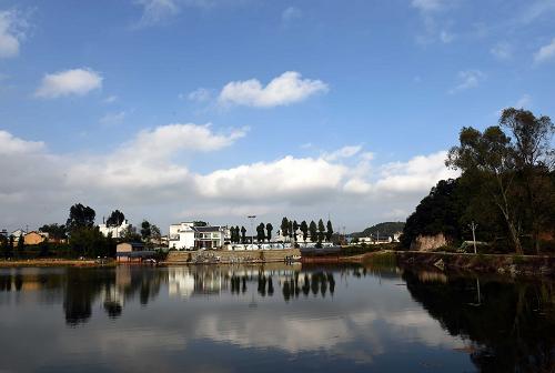 这是依山傍水的砚山县盘龙乡法土龙村（12月10日摄）。云南省文山壮族苗族自治州砚山县法土龙片区是一个以壮族、彝族、苗族为主体的多民族聚居区，共有农户854户4100余人。从2012年开始，在国家和当地政府的扶持下，法土龙片区的法土龙、响水龙、白石岩3个少数民族村寨启动实施精准扶贫“民族团结示范创建项目”。在项目规划建设中，当地政府推进危房改造、村中道路、人畜饮水、环境美化等民生工程，着力解决群众住房难、行路难、饮水难等生产生活条件问题。在产业扶持发展上，当地政府按照“适应市场、因地制宜、发挥优势、突出特色”的思路，引导群众发展三七、辣椒种植等传统产业项目，积极引进种草养畜、农家乐、樱桃种植等特色产业。2014年，3个少数民族自然村寨的年人均纯收入达到7181元。如今的砚山县盘龙乡法土龙片区3个自然村分别建成壮族特色农业旅游观光示范村，苗族民俗文化活动、饮食体验示范村，彝族特色原生态文明和谐示范村。