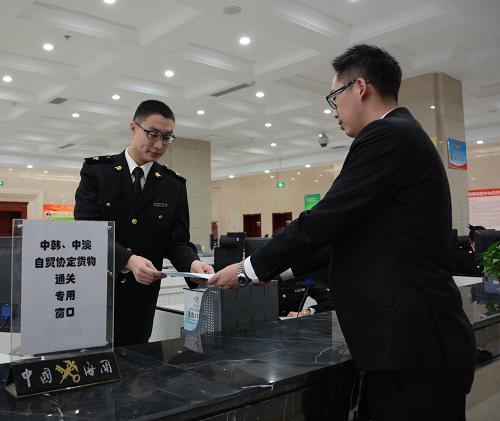 12月20日，货代公司工作人员向青岛大港海关工作人员递交《中韩自贸协定》正式生效后中国首票进口货物报关单。