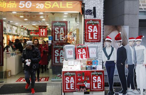 12月19日，在韩国首尔，人们从一家打折的化妆品商店里走出。