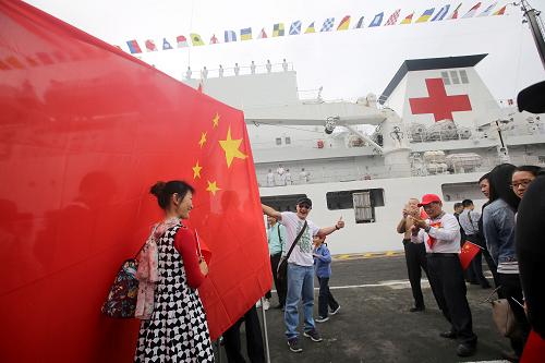12月20日，中国海军和平方舟医院船抵达秘鲁卡亚俄港，华人华侨以国旗为背景拍照留念。新华社发(江山 摄)