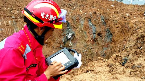 12月22日，在深圳光明新区滑坡灾害救援现场，武警水电部队官兵利用“蛇眼生命探测仪”对任务区进行搜救（手机拍摄）。新华社发（谭明裕 摄）