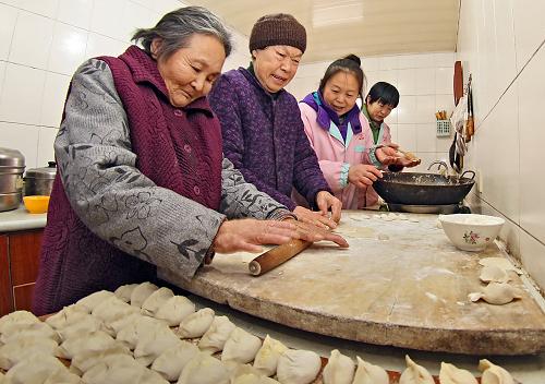 敬老院的老人正与护理人员一起包饺子,我国北方有过冬至吃饺子的习俗