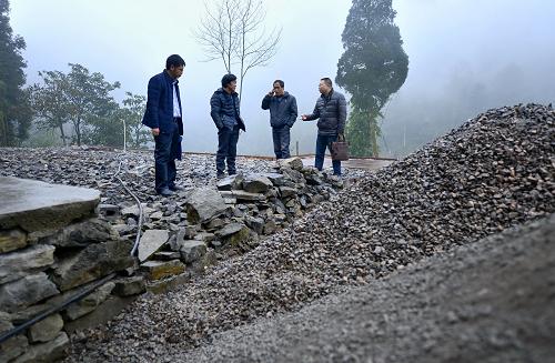 12月22日，湖北省宣恩县县办公室“扶贫家长”谭发军（右一）在椒园镇石马村贫困农民曾召毅（左二）的房屋整修现场了解施工进度。新华社发（宋文 摄）