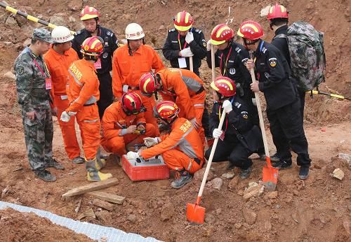 12月23日，天狼救援队（黑衣）和武警官兵一起使用生命测试仪。在深圳滑坡灾害发生后，除了解放军和武警部队的救援力量，灾害现场还活跃着多支志愿者专业救援队伍。他们与解放军和武警部队相配合，用专业的技术手段和技术能力开展救援。新华社记者 殷刚 摄