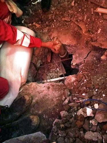 12月23日，在深圳滑坡事故现场，救援人员罗星星拉着田泽明的手，鼓励他坚持下去（手机拍摄）。