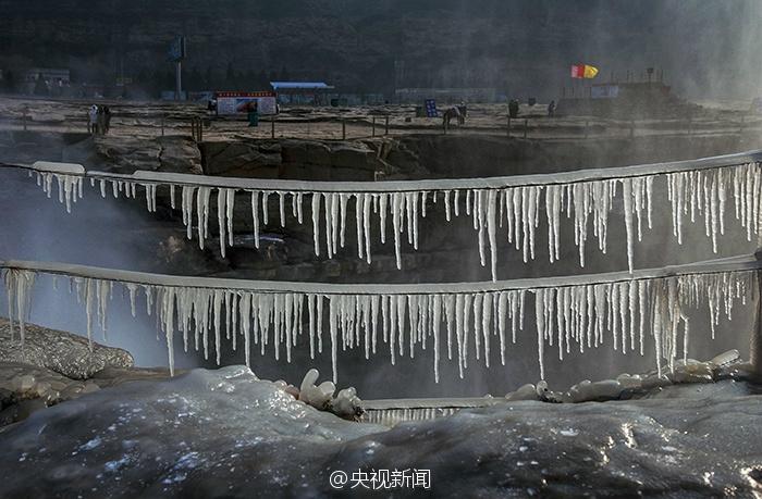 近日受持续降温影响，黄河壶口瀑布出现冰挂美景。这些冰挂都是黄河水从瀑布倾泻而下，冒起的水雾迅速冻结而成。依悬瀑布两岸的冰挂晶莹剔透、造型各异，有的像龙须，垂悬在岩石上；有的如无暇白玉，镶嵌在河岸旁。