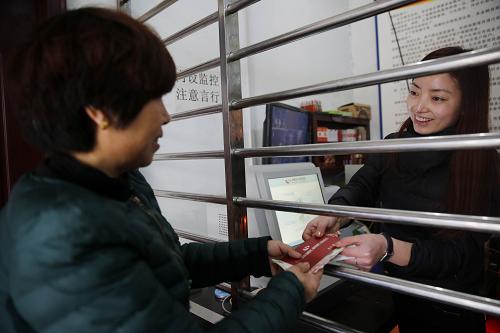 12月27日，在河南省宝丰县赵庄镇袁庄村农民金融自助服务点，村民岳丽花（左）在办理粮食直补金领取业务。