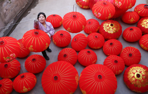 12月30日，在河南省武陟县西陶镇东滑封村“廉火灯笼”作坊，一名村民将制作好的灯笼挂起晾晒。