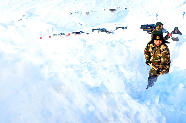 1月3日，边防官兵用铁锹清理积雪。1月3日11时25分，新疆公安边防总队阿勒泰边防支队冲乎尔边防派出所接到电话报警，S232喀拉塔斯盘山道有车辆遭遇雪崩被埋，道路被堵塞，20余辆车被困。随后，边防官兵携带救援工具火速赶赴现场。经过4个多小时的共同努力，最终成功将被困车辆解救。目前，被困车辆和人员已脱险。新疆阿勒泰地区近期遭遇十年不遇的罕见暴雪袭击，连续15天的降雪导致布尔津县部分山区积雪高达2米。新华社发（石晓坤 摄）