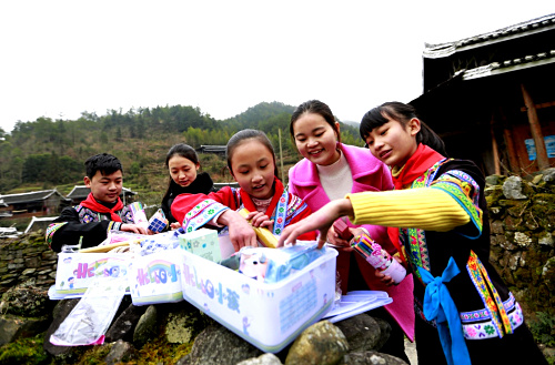 1月12日，湖南省城步苗族自治县长安营乡民族中心学校的学生在回家路上和老师（右二）察看爱心礼物。当日，中国儿童少年基金会携手安利公益基金会，来到湖南省城步苗族自治县长安营乡民族中心学校，向苗族侗族贫困儿童及留守儿童发放“HELLO小孩”爱心套餐。“HELLO小孩”爱心套餐公益项目由中国儿童少年基金会推出，主要为困难儿童提供多种学习生活必需品。此次活动将投入50万元定向为湖南贫困地区儿童赠送2500套“HELLO小孩”日常套餐，并为这些孩子普及营养知识，帮助他们健康成长。新华社记者 潘旭 摄