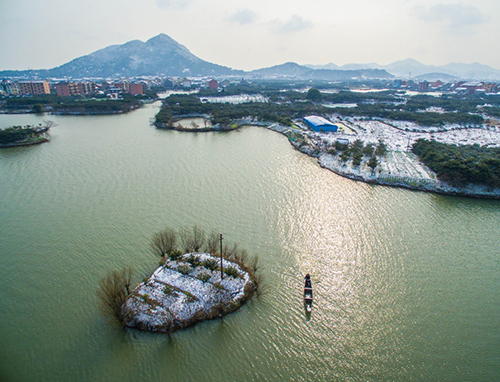 1月23日，一艘小船划过杭州塘栖镇丁山河村覆盖着白雪的水中小岛。当日， 浙江省气象台发布寒潮橙色预警，高强度寒潮已逐渐影响浙江全省，杭嘉湖地区气温已降至最低-2～-5℃，且气温将继续下降，部分地区可能突破或接近历史极值。