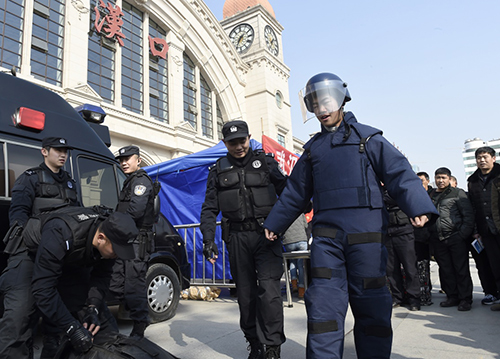 1月23日，在汉口火车站广场举行的春运安全宣传活动上，一名旅客在特警指导下穿着搜爆服行走。