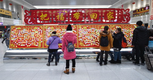 1月28日，旅客们在“春运寄语墙”前驻足观看。长春市火车站候车室在春运期间设立了“春运寄语墙”，让出行旅客写下祝福。春运开始5天来，这处长10米、高1.5米的双面墙已贴满了旅客们对家人的关怀、对新年的期待和对远方的思念。新华社记者 张楠 摄