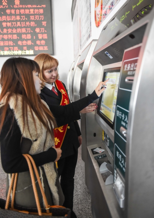 1月27日，来自俄罗斯符拉迪沃斯托克的志愿者玛丽娅（右）在引导旅客取票。新华社记者 王昊飞 摄