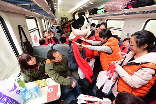 1月28日，“幸福列车”工作人员为旅客送上祝福的红围巾。