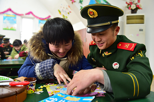 1月29日，武警战士杨盼望与儿童福利院的孩子玩拼图。