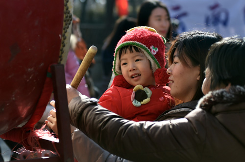 2月8日，一位小朋友在济南千佛山祈福会上敲鼓祈福。