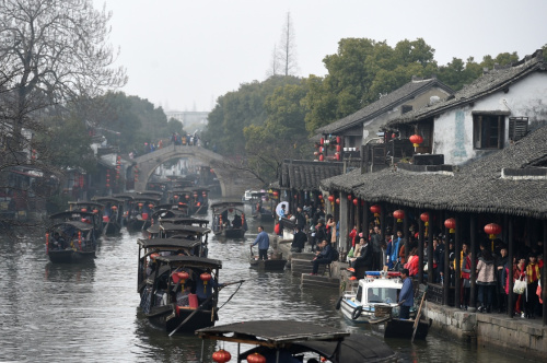 2月12日，游客乘坐游船在浙江西塘古镇穿行。当日是大年初五，位于浙江省嘉善县境内的西塘古镇持续迎来大批游客。在春节期间，西塘景区每日举办祭灶神、水上婚礼等特色民俗活动，让游客感受到浓浓的传统年味。新华社记者 黄宗治 摄