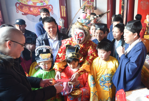 2月12日，“福建猴王”黄东闽扮演的“大圣”领着五路小财神在福州天后宫给游客派发“银元宝”。新华社记者 林善传 摄
