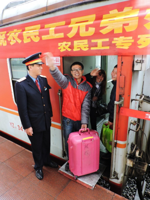 2月12日，登上“农民工南下专列”的旅客与送行亲友挥手告别。新华社发（邓良奎 摄）