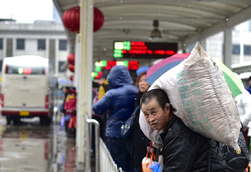 2月13日，一名乘客背着行李在天津站公交车站候车。天津当日迎来降雪天气。新华社记者 岳月伟 摄
