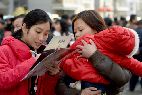 2月18日，在合肥市滨湖新区春风行动第十二届滨湖新区大型招聘会现场，回迁居民孙永华（右）抱着自己3岁大的孩子前来登记应聘信息，她想找一个小时工的工作。新华社记者 郭晨 摄