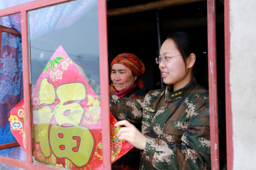 2月19日，边防派出所民警和热合木·别尔地的妻子一同在贴“福”字。新华社发（贾航超 摄）