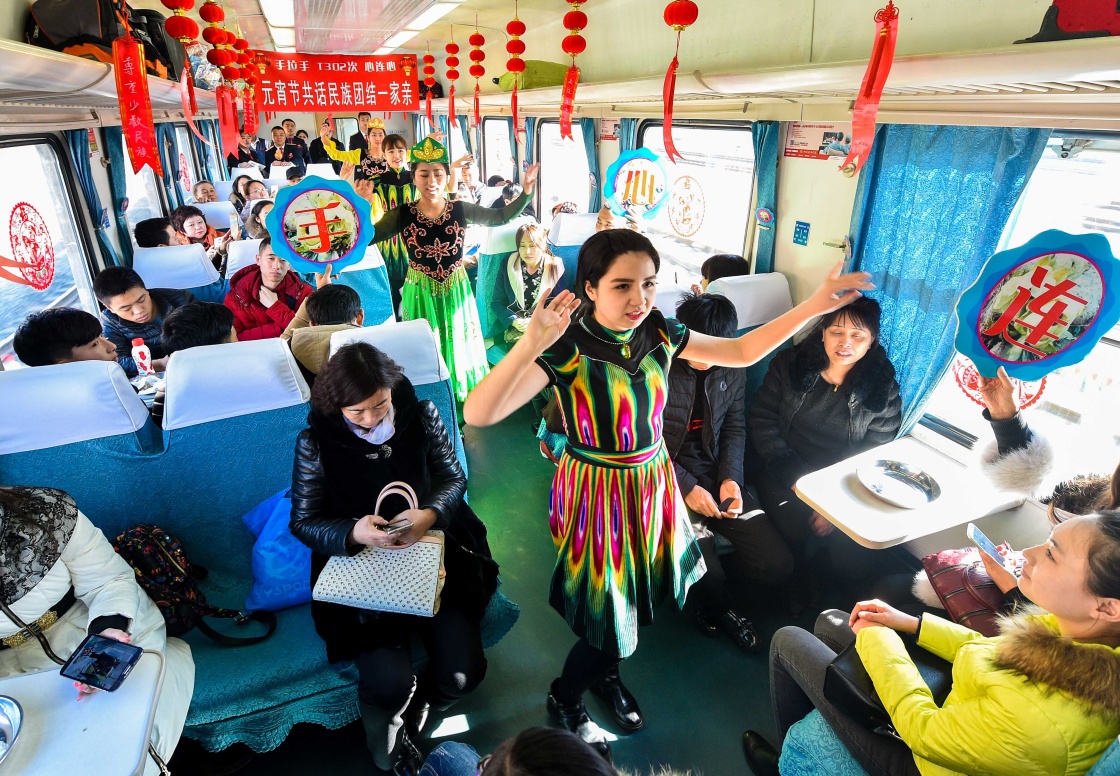 2月21日，乘务员与维吾尔族学生在车厢内跳舞。当日，由长春开往乌鲁木齐的T302次旅客列车上举办了一场“元宵佳节喜乐会”，长春客运段的乘务员与旅客猜灯谜互动，共同进行文艺表演，在车厢里营造喜庆的节日气氛。新华社记者 许畅 摄