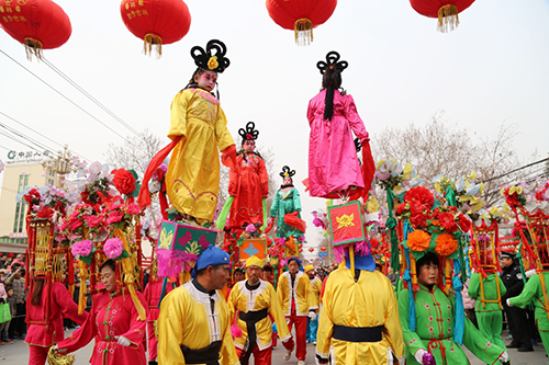 2月23日，河南省温县赵堡镇赵堡村民间艺人在街头巡演“背桩行水”。当日是农历正月十六，河南省温县赵堡镇赵堡村民间艺人进城表演“背桩行水”传统民俗节目庆新春。温县赵堡镇赵堡村“背桩行水”是起源于清代的一种民间艺术形式。“背桩”是将童男、童女固定在桩架上，由成年人扛桩架进行表演。“行水”则是表演者用头顶装满鲜花、彩带的八角亭式的水架进行表演。表演者多走“一条鞭”“二龙出水”“八字花”等队形，形式别具一格，场面热闹。