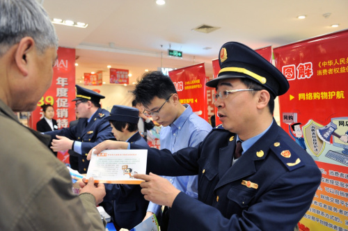 3月11日，北京月坛工商所干部（右一）在长安商场向市民介绍网购维权提示。在“3·15”国际消费者权益日到来前，北京市月坛工商所和多家质检机构合作设立的“新消费”维权宣讲台走进商场，宣讲相关法律法规和政策措施，以适应传统消费模式向智能电子、旅游休闲、信息服务等为代表的新消费领域转型升级情况下，消费维权的新趋势，提升消费者权益保护水平。新华社记者 张旭 摄