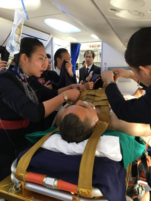 3月27日，在老挝首都万象瓦岱国际机场，工作人员为一名中国伤员系安全带（手机拍摄）。新华社发（任保国 摄）