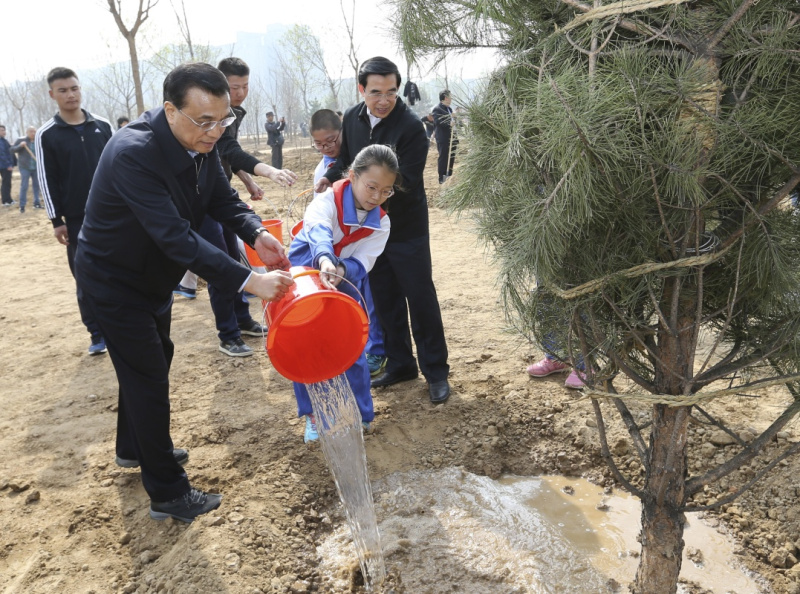 这是李克强同少先队员一起给刚栽下的树苗浇水。新华社记者 马占成 摄