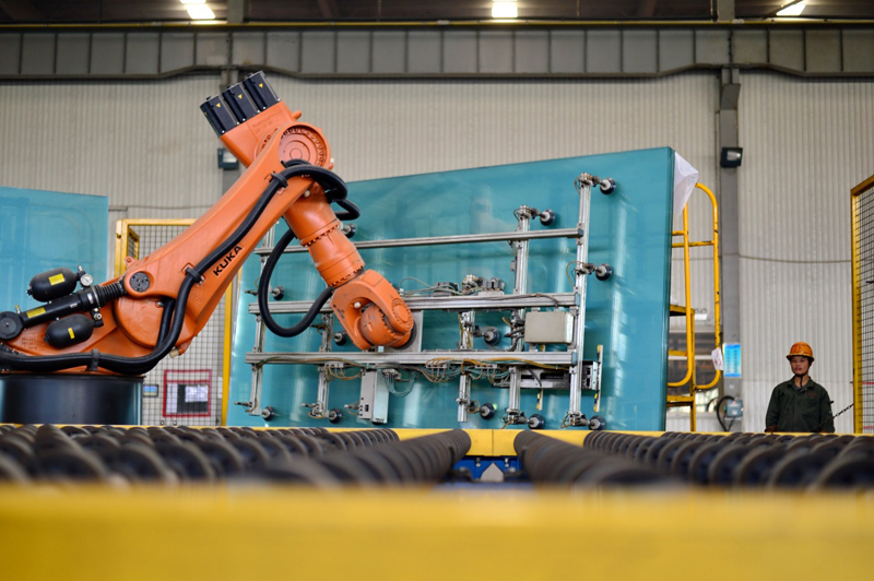 河北省沙河市一家玻璃生产企业自动化生产线上的机械手臂在装运玻璃