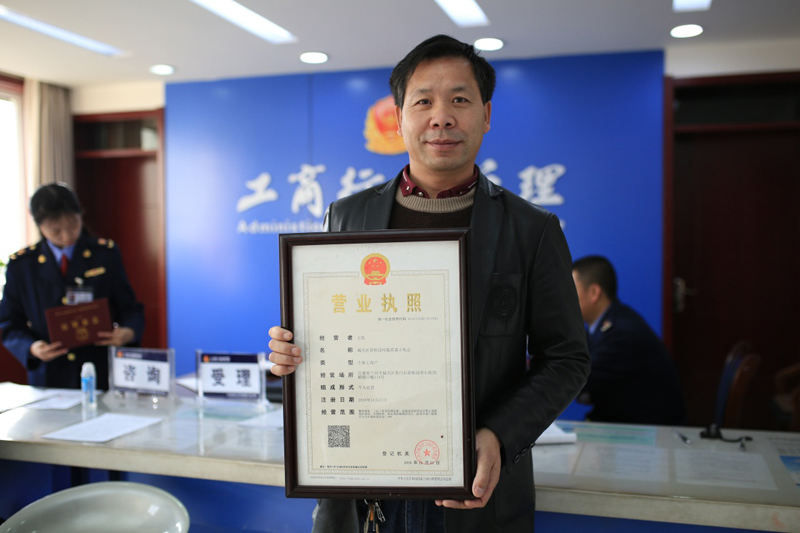 个体工商户王凯在展示刚颁发的带有统一社会信用代码的"两证整合"营业