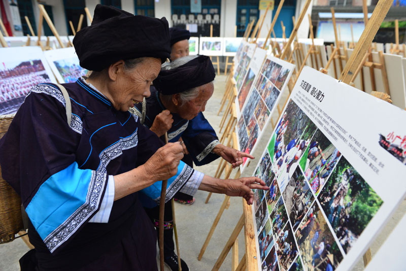 7月13日,贵州省剑河县磻溪镇小广侗寨的村民在观看摄影展.