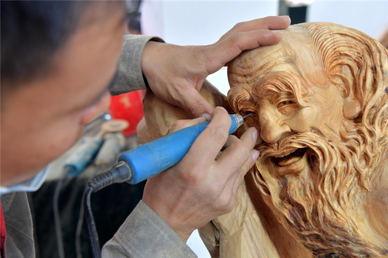 在江西省余江县的大赛操作车间,参赛选手在精心雕刻自己的根雕作品(11