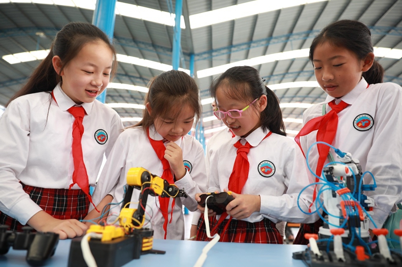 8月12日,小学生在科技嘉年华活动上操控机器手模型.