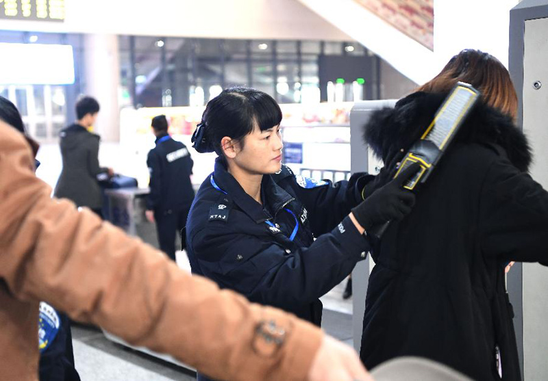 2月15日,安检人员在南宁东站用安检探测仪为乘客安检.