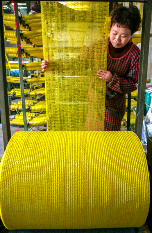 3月18日,大宫殿村村民在网袋编织机旁作业.