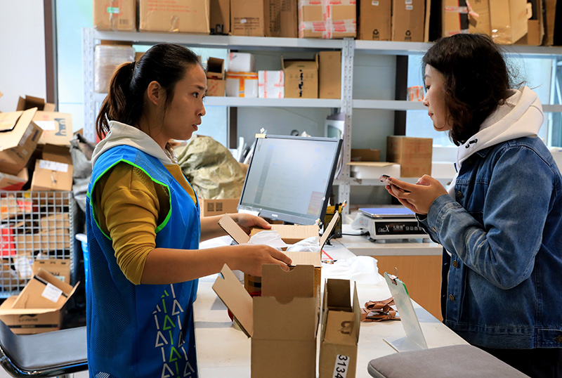 11月13日,驿站寄件员(左)使用回收纸盒帮顾客包装需要快递的物品.