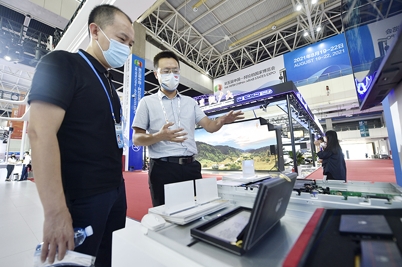 8月20日,参展商工作人员(右)在中阿博览会银川国际会展中心展区介绍