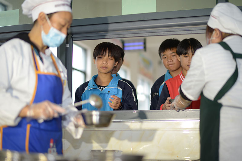 10月12日,在贵州省遵义市绥阳县风华镇中心学校食堂,工作人员在给学生