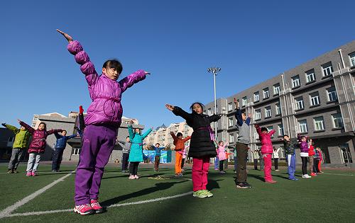 2月27日,北京市东城区西总部小学的学生们在操场上做操。 新华社发(周良 摄)