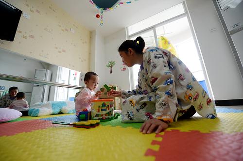 3月3日,西安儿童福利院的工作人员陪伴收治的弃婴玩耍。新华社记者 李一博 摄