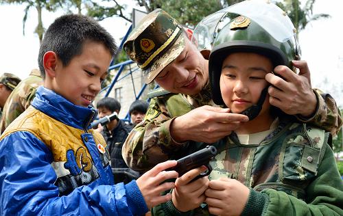3月13日,小学生们在边防民警指导下穿戴警用服装。当日,福建省福清市元载中学、海口镇中心小学的三十多名留守学生走进福清市公安边防大队警营,学习日常生活中常用的安全防范知识,参观警用装备,零距离感受警营生活。新华社记者 魏培全 摄