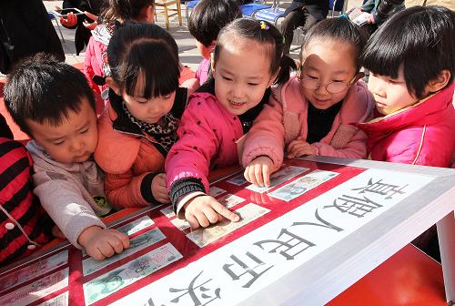 3月12日,新疆哈密机辆路社区幼儿园的小朋友在了解真假币识别方法。当日,中国人民银行哈密地区支行在机辆路社区开展“四讲四送”金融知识宣传服务活动,向居民介绍信用贷款、还款操作流程、支农信贷产品、防止诈骗及假币辨别技巧等,普及金融知识。新华社发(普拉提 摄)