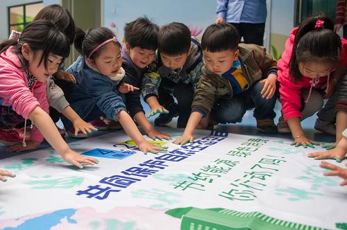 4月21日,合肥市天鹅幼儿园的小朋友在主题画布上按手印。新华社记者 杜宇 摄